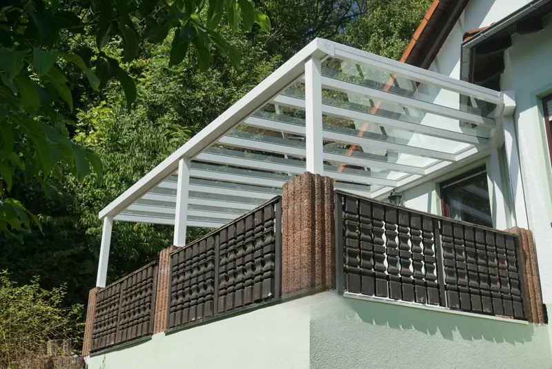 Białe zadaszenie balkonu ze szklanym dachem i dekoracyjną balustradą