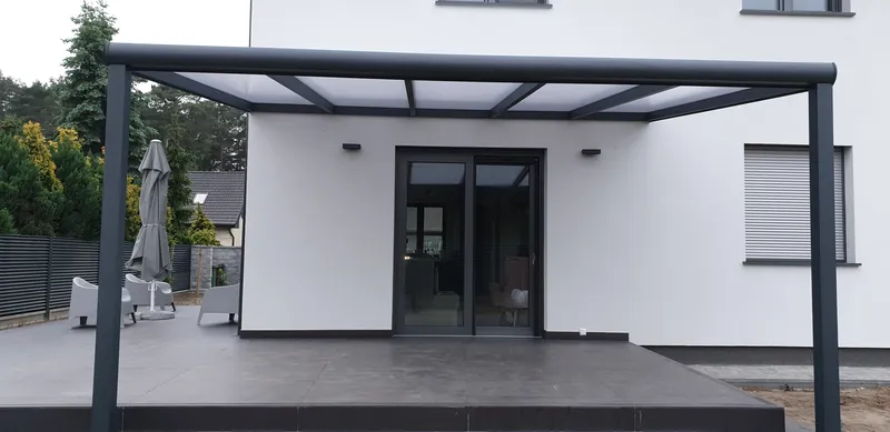 Aluminiowe zadaszenie tarasu z dachem z poliwęglanu opal przy białym nowoczesnym domu